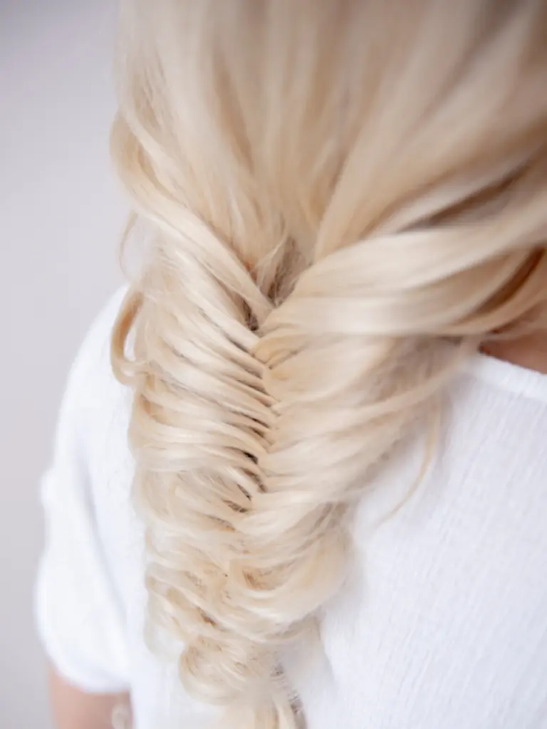 Irina Rico, con una clienta en su domicilio para peluquería Mostrando peinado con trenza espiga suelta sobre cabello rubio largo.